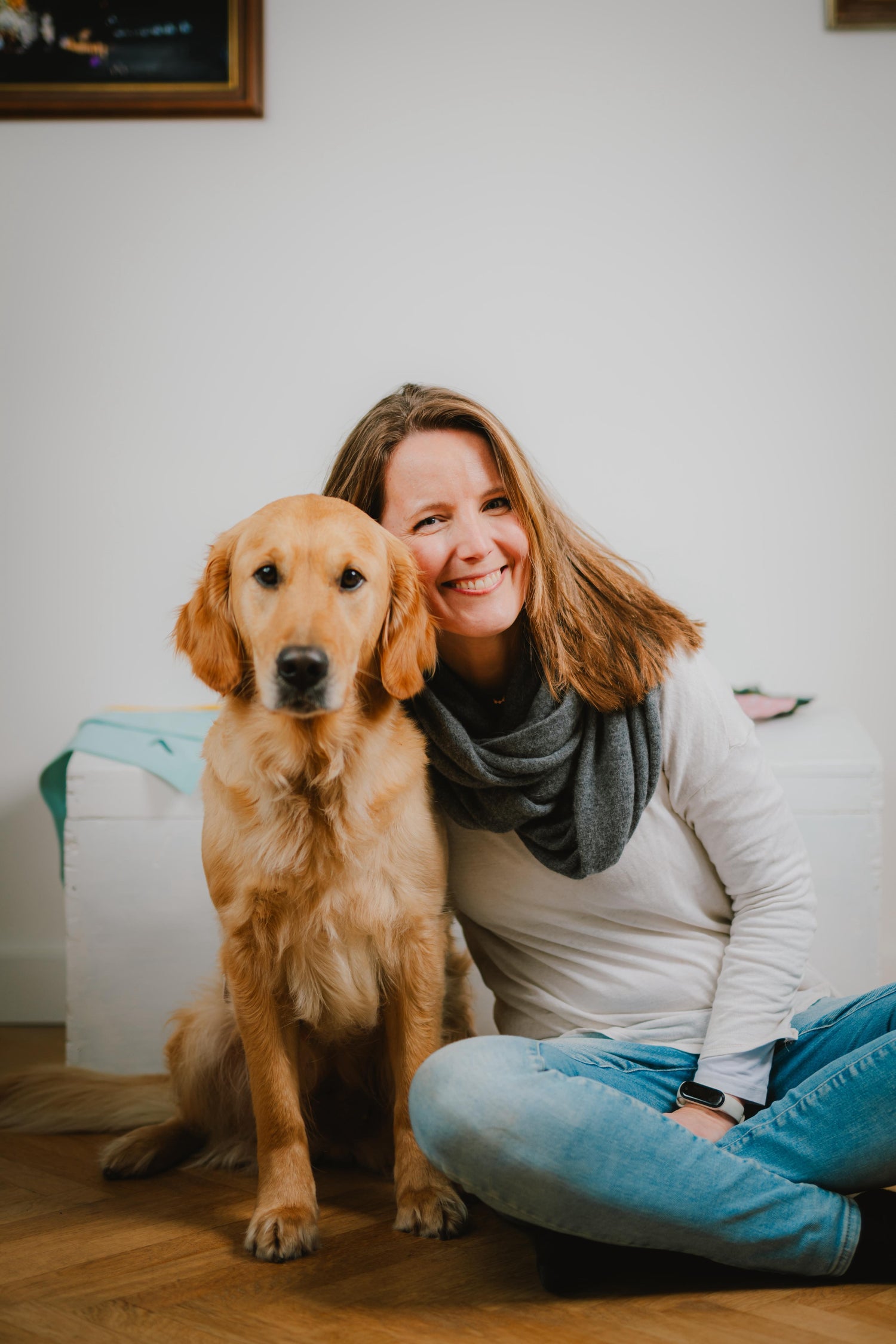 Eine Frau und ein Hund sitzen auf dem Boden und schauen in die Kamera